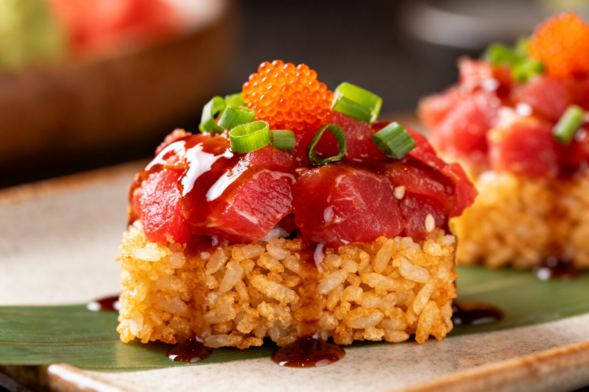 Air fryer crispy rice spicy tuna topped with diced tuna, spicy sauce, green onions, and fish roe, served on crispy golden rice squares.
