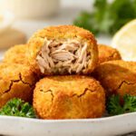 Air fryer tuna croquettes with a crispy golden breadcrumb coating and tender flaky tuna filling, served with lemon wedges and fresh parsley on a white plate.