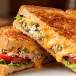 Air fryer tuna melt sandwich with flaky tuna, melted cheddar cheese, celery, lettuce, and tomato on crispy golden toasted bread.