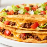 Air fryer Taco Bell Mexican pizza layered with seasoned ground beef, melted cheese, diced tomatoes, and shredded lettuce between crispy tortillas.
