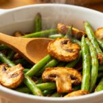 Air fryer green beans and mushrooms roasted until tender with lightly crispy edges, tossed together in a serving bowl for a simple and savory vegetable side dish.