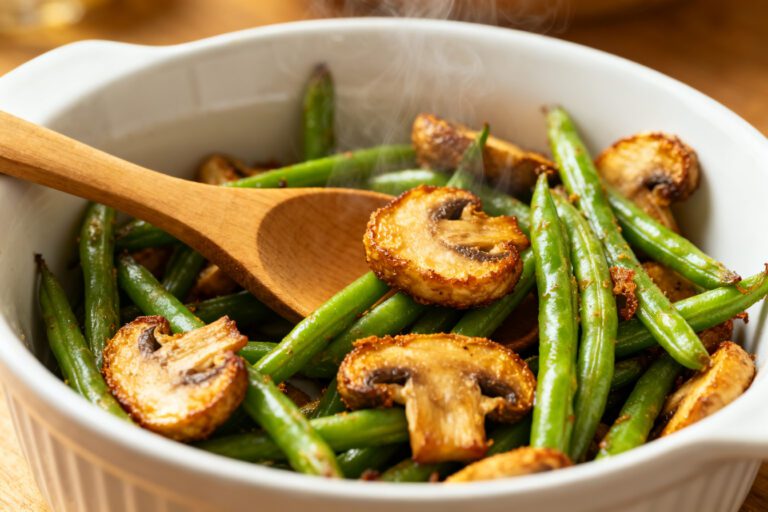 Air fryer green beans and mushrooms roasted until tender with lightly crispy edges, tossed together in a serving bowl for a simple and savory vegetable side dish.