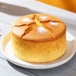 Air fryer sponge cake with a light and fluffy texture, golden brown top, and delicate crumb, dusted with powdered sugar and served on a white plate.