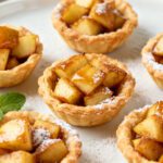 Air fryer apple cinnamon bites baked in flaky pastry cups and filled with warm cinnamon apples, finished with powdered sugar for an easy dessert.