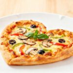 Air fryer heart shaped pizza topped with melted mozzarella cheese, mushrooms, black olives, bell peppers, and fresh basil on a crispy golden crust.