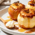 Air fryer baked apples with tender roasted apples, warm cinnamon spice, and a sweet caramel drizzle, served with a dollop of cream for a cozy homemade dessert.