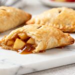 Air fryer apple turnovers with pie crust featuring a flaky golden pastry, warm cinnamon apple filling, and caramelized apple pieces peeking from the crispy crust.