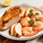Air fryer chicken and shrimp with juicy seasoned chicken breast, tender shrimp, and fresh parsley, served on a platter for an easy surf and turf style dinner.