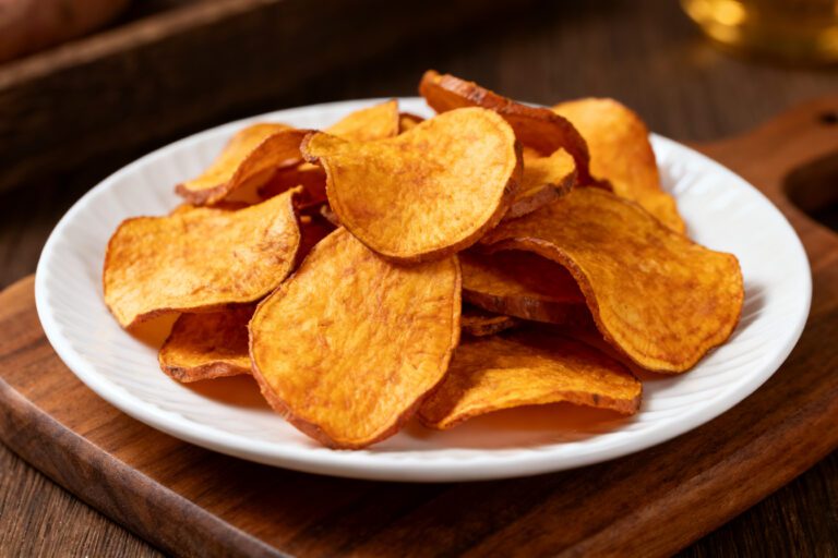Air fryer sweet potato chips with crispy golden edges, thinly sliced sweet potatoes, and a light crunchy texture, served on a white plate as a healthy snack.