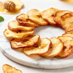 Air fryer apple chips with thinly sliced apples dried until crispy and lightly golden, arranged on a plate as a naturally sweet and healthy homemade snack.