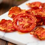Air fryer tomato chips with thinly sliced tomatoes roasted until crispy, featuring a rich savory flavor and crunchy texture, served as a healthy homemade snack.