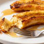 Air fryer fried bananas with caramelized golden edges, a tender creamy center, warm cinnamon, and a drizzle of honey, served as a quick and comforting dessert.