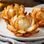 Air fryer mini blooming onions with crispy golden petals, crunchy seasoned coating, and tender onion centers, served on a plate as a fun and shareable appetizer.