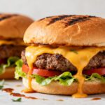 Air fryer homemade hamburgers with juicy beef patties, melted cheddar cheese, fresh lettuce, tomato slices, and toasted buns, served as a classic family friendly meal.