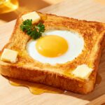 Air fryer egg in a hole with a perfectly cooked sunny side egg in the center of crispy golden toast, served with butter and a drizzle of honey for a cozy breakfast.