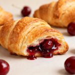 Air fryer cherry croissants with flaky golden pastry and a sweet cherry filling, featuring juicy cherries and a crisp buttery exterior, served with fresh cherries.