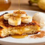 Air fryer banana dessert with a golden caramelized base, creamy banana topping, honey drizzle, and a scoop of vanilla ice cream, served as a cozy and comforting sweet treat.