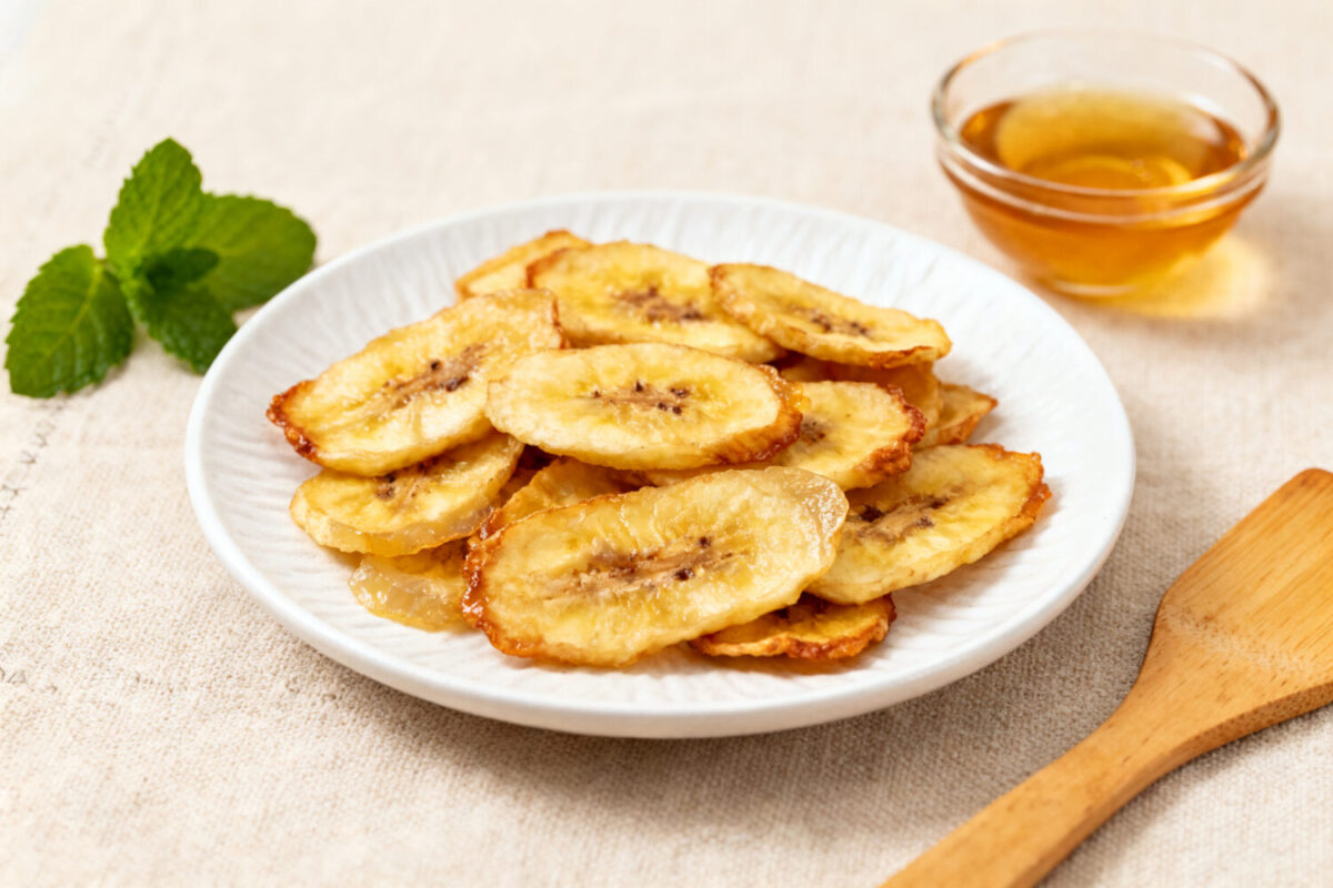 Air fryer dehydrated bananas with thin banana slices dried until lightly crisp and naturally sweet, served on a plate with honey for a simple and healthy snack.
