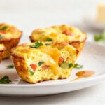 Air fryer egg bites with a fluffy egg texture, melted cheese, colorful diced vegetables, and golden edges, served as a quick high protein breakfast or snack.