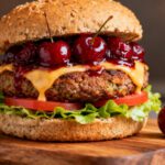 Air fryer cherry veggie burger with a hearty vegetable patty, melted cheese, fresh lettuce, tomato slices, and a sweet cherry topping on a toasted whole grain bun.