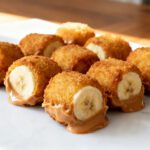 Air fryer banana peanut butter bites with banana slices coated in a crispy golden crumb topping and creamy peanut butter, served as a crunchy sweet snack or dessert.