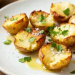 Air fryer smashed mini potatoes with crispy golden edges, fluffy potato centers, flaky sea salt, fresh parsley, and a drizzle of olive oil, served as an easy and flavorful side dish.