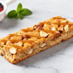 High protein air fryer bars made with oats, nuts, and protein rich ingredients, topped with a creamy drizzle and chopped nuts, served as a filling snack or post workout treat.