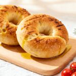 High protein air fryer bagels with a chewy golden crust, protein packed dough, and a lightly seasoned topping, served on a wooden board as a satisfying breakfast or snack.