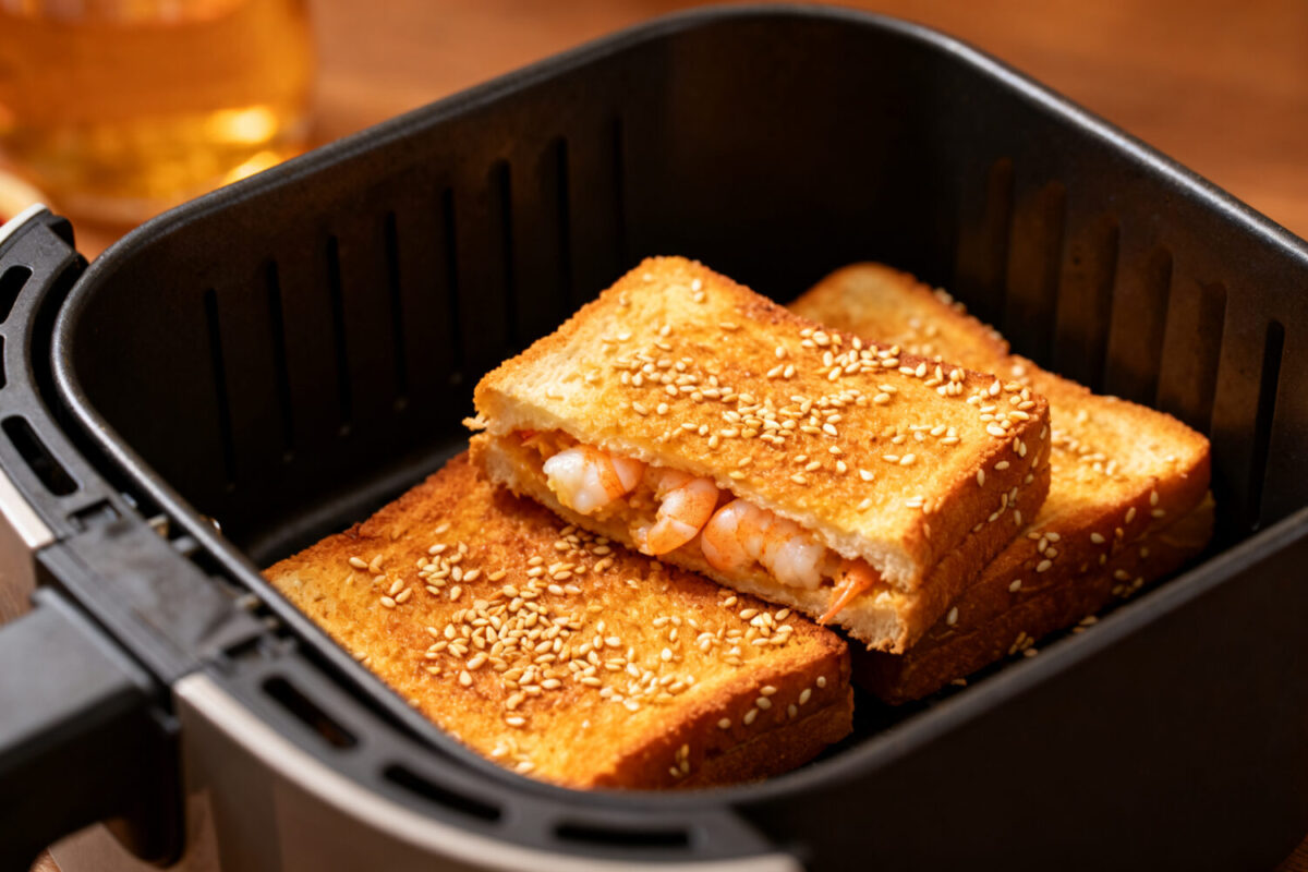 Sesame prawn toast in the air fryer with crispy golden bread coated in toasted sesame seeds and filled with savory shrimp, cooked until crunchy and golden inside an air fryer basket.
