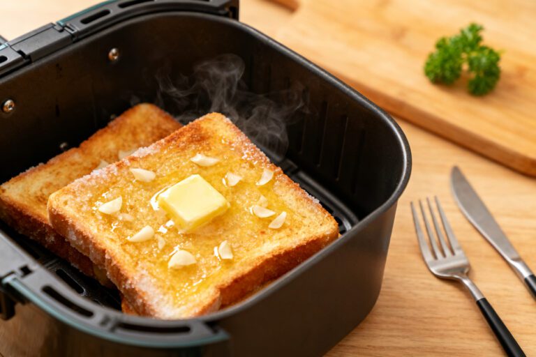Frozen garlic toast cooked in the air fryer with a crispy golden buttery surface, toasted garlic pieces, melted butter, and steaming hot bread, served fresh from an air fryer basket.