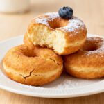 High protein Greek yogurt donuts made in the air fryer with a fluffy tender texture, golden exterior, and light dusting of powdered sugar, served as a healthier protein packed sweet treat.