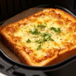 Garlic toast pizza made in the air fryer with crispy garlic bread, melted golden cheese, Italian herbs, and toasted edges, cooked inside an air fryer basket for a quick and satisfying meal.