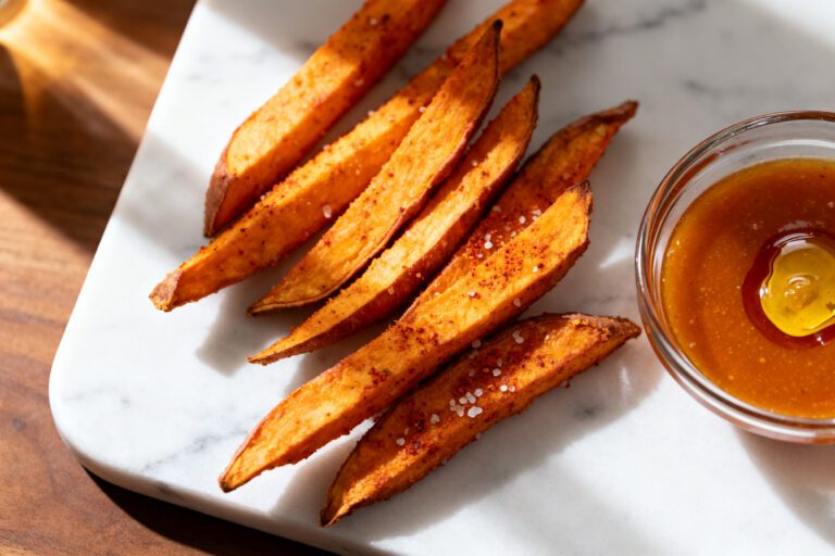 Air fryer sweet potato fries served with a creamy dipping sauce, featuring crispy roasted sweet potato wedges with caramelized edges, flaky sea salt, and a sweet and tangy glaze.