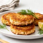 Air fryer canned salmon cakes with crispy golden brown crusts, tender flaky salmon, fresh dill, and lemon wedges, served as a budget friendly seafood meal or appetizer.