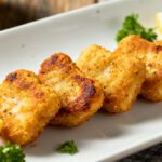 Frozen chicken nuggets cooked in the air fryer with a crispy golden brown coating, juicy tender chicken inside, and lightly seasoned crunchy edges, served with lemon wedges and fresh parsley.