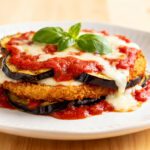 Air fryer eggplant Parmesan with crispy breaded eggplant slices layered with rich marinara sauce, melted mozzarella cheese, and fresh basil, served as a lighter Italian inspired dinner.