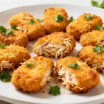 Air fryer shredded chicken nuggets with a crispy golden coating, juicy shredded chicken filling, fresh parsley garnish, and lemon wedges, served as an easy high protein snack or family friendly meal.