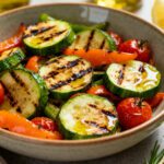 Air fryer grilled vegetables with zucchini, bell peppers, and cherry tomatoes featuring smoky grill marks, tender crisp texture, fresh herbs, and a light olive oil drizzle, served as a colorful and flavorful side dish.