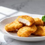 Air fryer chicken nuggets without breading with juicy tender chicken, a lightly golden seasoned exterior, fresh parsley garnish, and lemon wedges, served as a simple high protein meal.