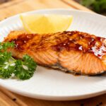 Air fryer honey teriyaki salmon with a flaky tender salmon fillet, glossy honey teriyaki glaze, fresh parsley garnish, and lemon wedge, served as a flavorful and healthy seafood dinner.