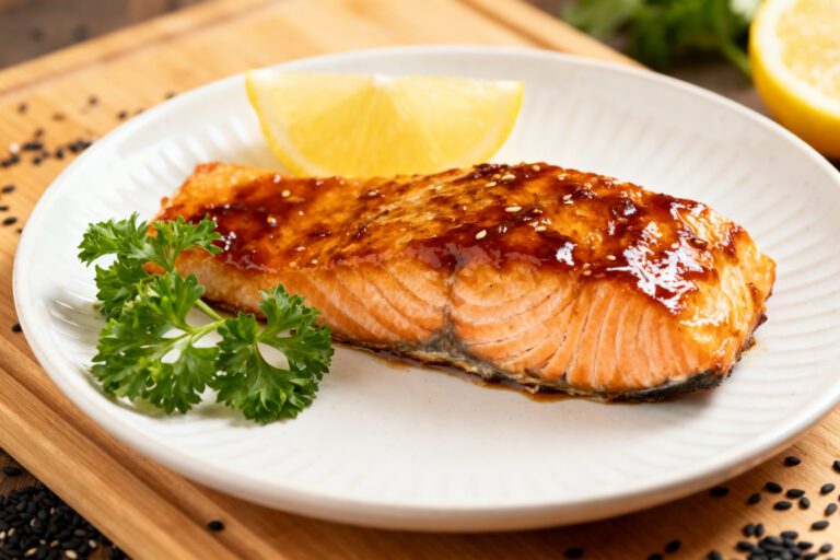 Air fryer honey teriyaki salmon with a flaky tender salmon fillet, glossy honey teriyaki glaze, fresh parsley garnish, and lemon wedge, served as a flavorful and healthy seafood dinner.