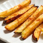 Air fryer veggie fries with crispy golden vegetable sticks, lightly seasoned coating, caramelized edges, fresh parsley garnish, and a lemon wedge, served as a colorful and healthy side dish.