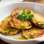 Air fryer veggie fritters with crispy golden edges, tender vegetable filled centers, shredded zucchini and carrots, fresh parsley garnish, and a light drizzle of olive oil, served as a healthy appetizer or side dish.