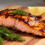 Air fryer BBQ salmon with a flaky tender salmon fillet, caramelized barbecue glaze, fresh dill garnish, and lemon wedges, served as a juicy and flavorful seafood dinner.