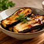Air fryer miso eggplant with tender roasted eggplant halves, a glossy savory miso glaze, caramelized edges, and fresh parsley garnish, served as a flavorful Japanese inspired side dish.