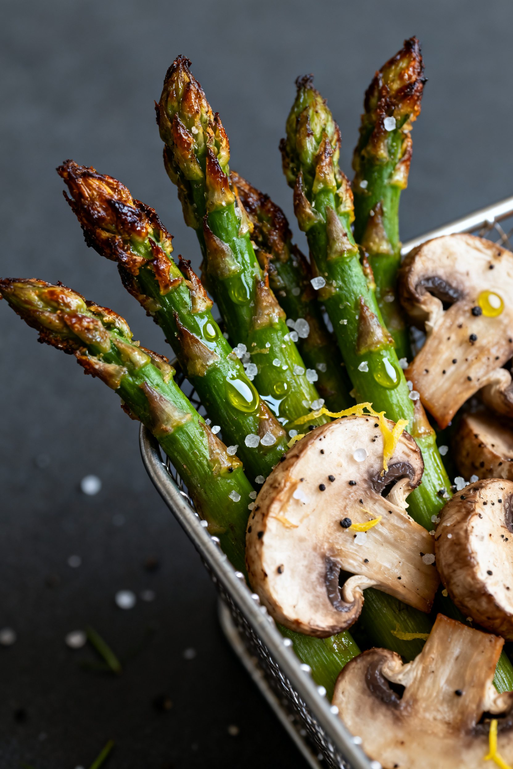 Close-up detail: Air-fried asparagus and sliced cremini mushrooms just out of the basket, tender-cri