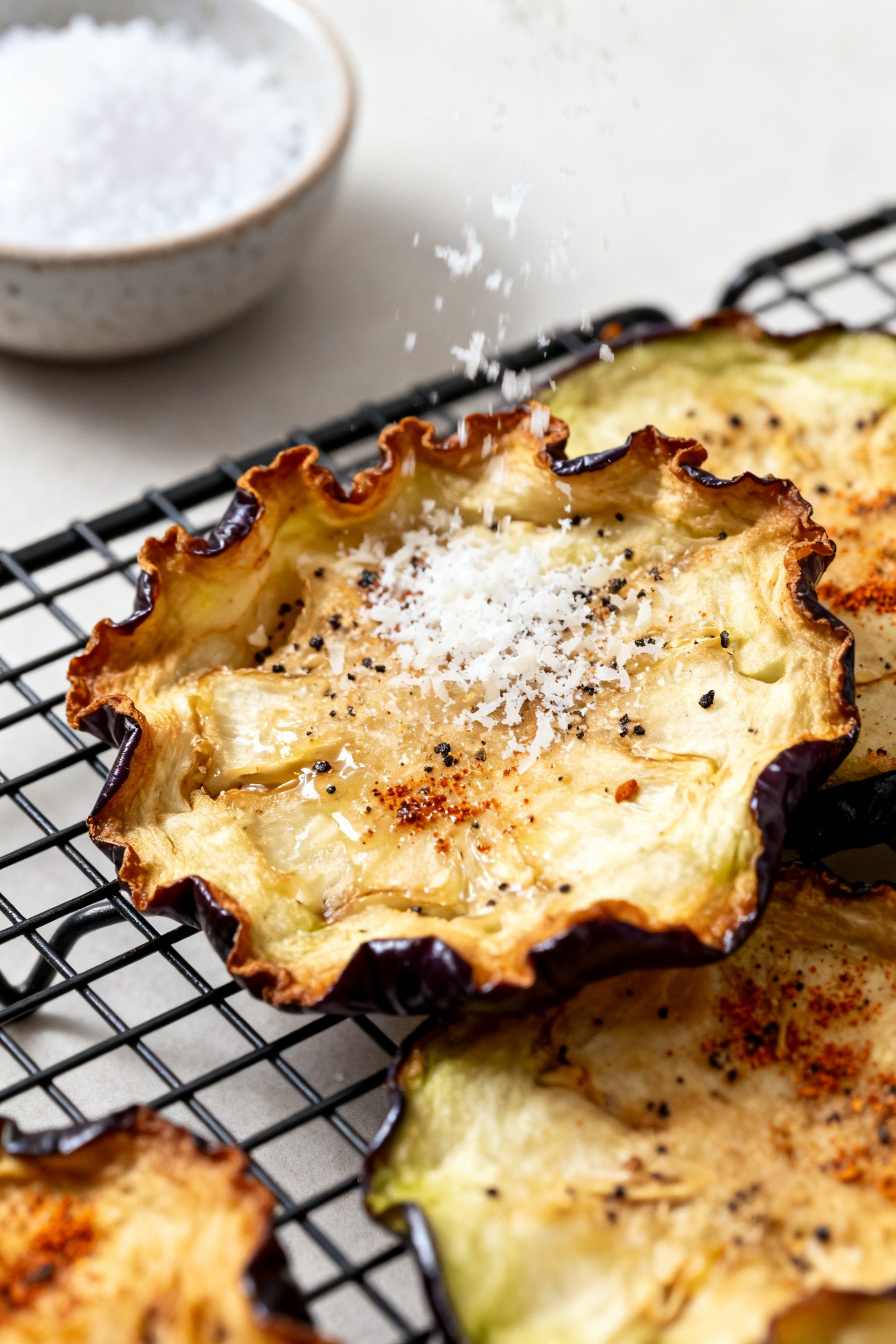 Close-up detail: Air fryer eggplant chips just out of the basket, golden-brown ruffled edges with a