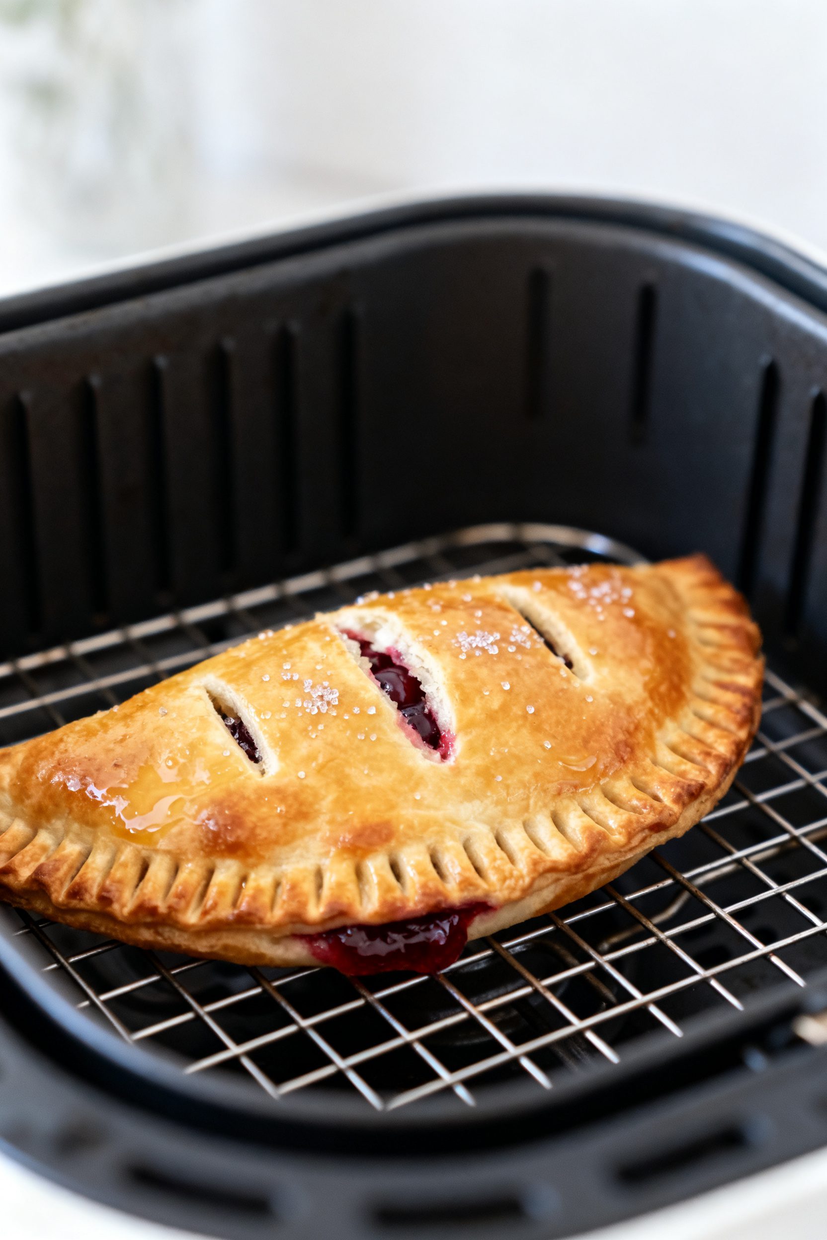 Close-up detail: Golden, air-fried cherry cheesecake hot pocket just out of the basket, deep golden 