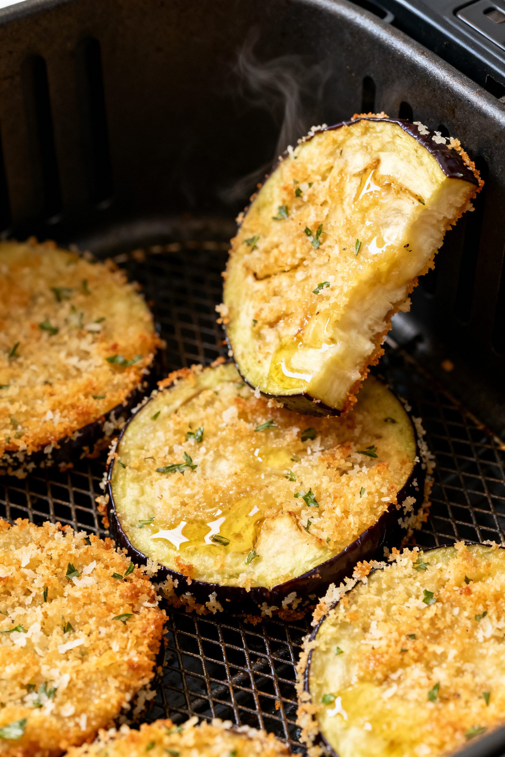 Close-up detail: Golden air-fried eggplant rounds just out of the basket, ultra-crispy panko-Parmesa