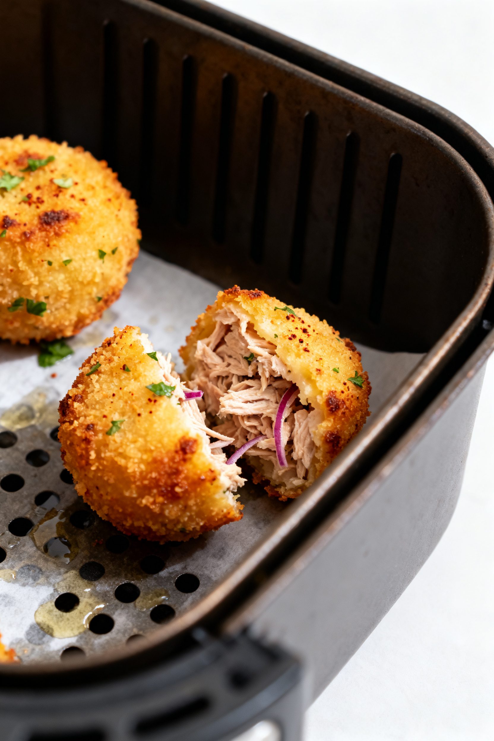 Close-up detail: Golden, air-fried tuna bites just out of the basket, edges crisp and blistered with